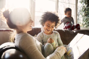 Une mere de famille avec sa fille en train de lire une histoire dans le salon assises sur un canape