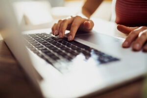 Gros plan sur les mains d'une femme sur le clavier d'un ordinateur portable.